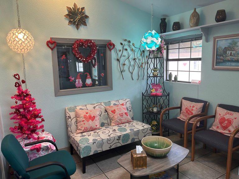 room with pale teal walls with 3 teal colored arm chairs and a flowery love seat